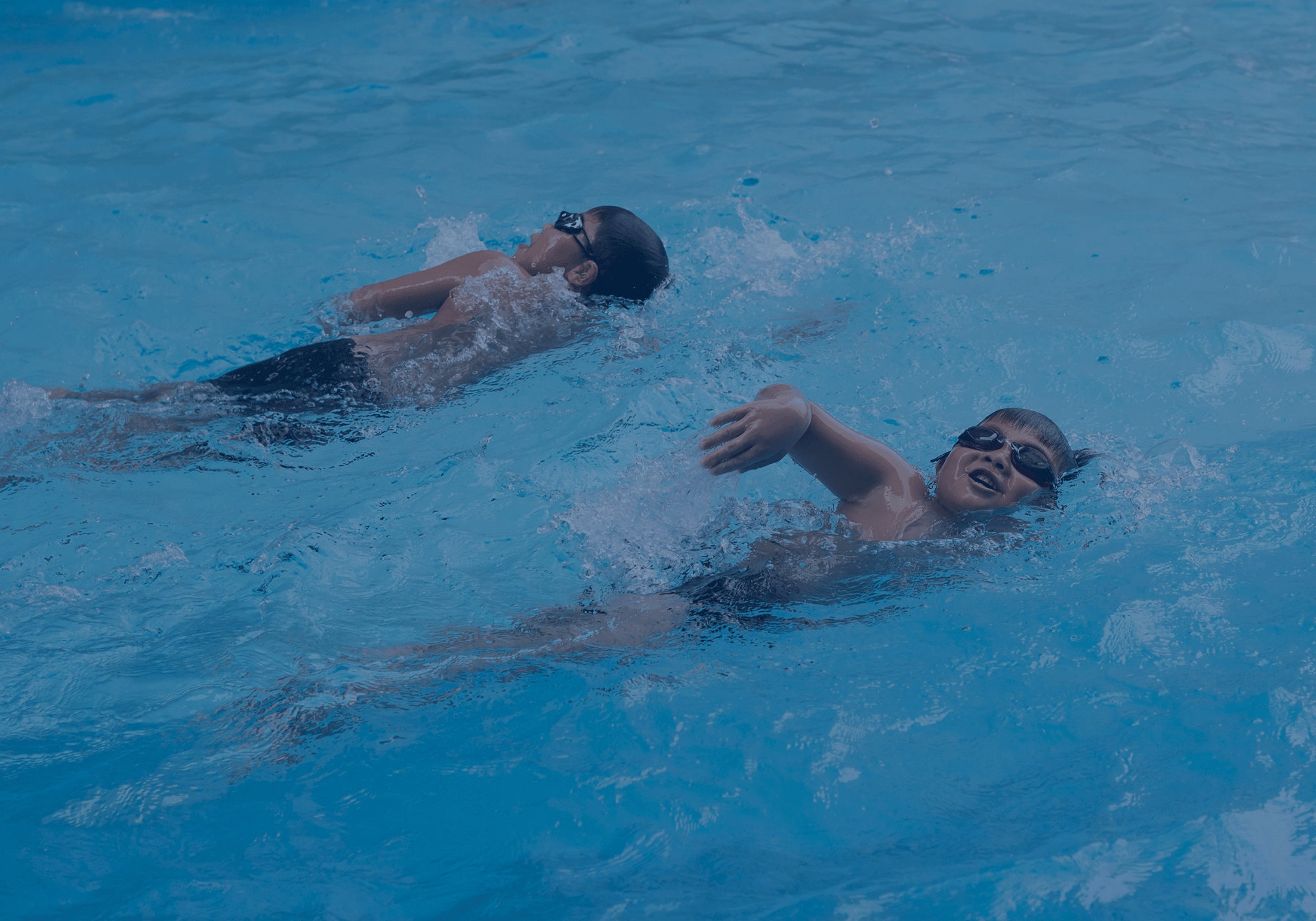Zwei Kinder beim Kraulschwimmen im Pool – Spaß und Techniktraining im Wasser.