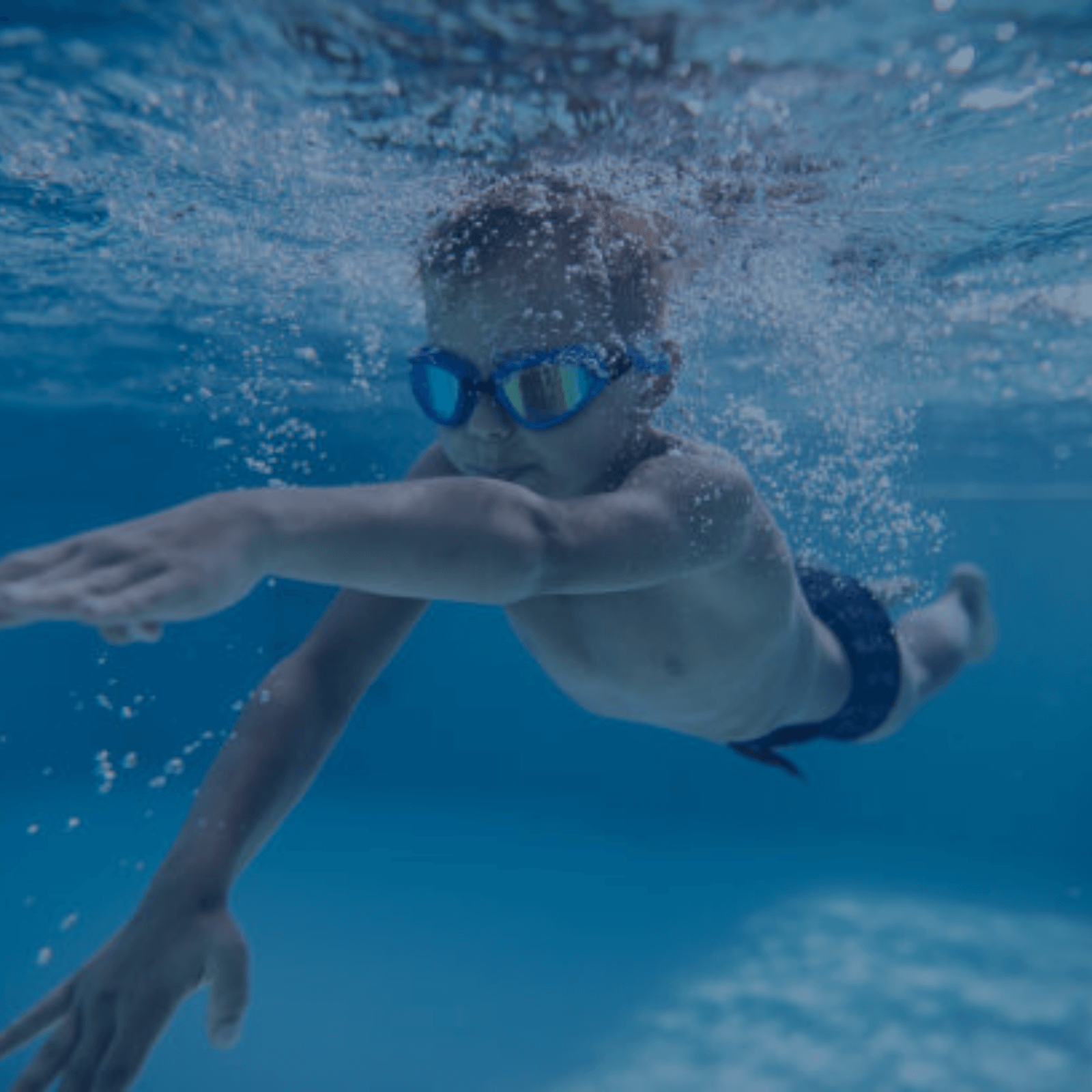 Kind mit Schwimmbrille taucht unter Wasser und entdeckt den Spaß am Schwimmen – AquaFit Schwimmkurse wecken Begeisterung schon von klein auf.